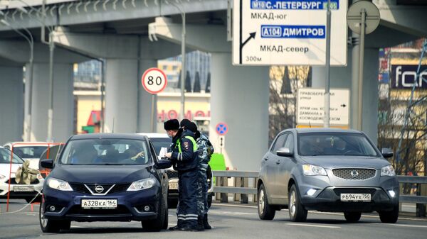 Сотрудник дорожно-патрульной службы ГИБДД проверяют документы у водителя на блокпосту при въезде в Москву 