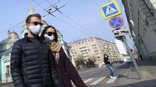 Молодые люди в защитных масках и перчатках на одной из улиц Москвы
