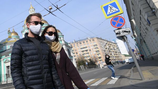 Молодые люди в защитных масках и перчатках на одной из улиц Москвы