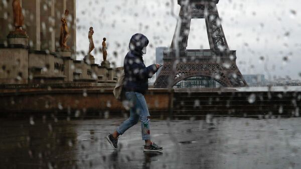 Женщина проходит мимо Эйфелевой башни в Париже во время пандемии вируса COVID-19 