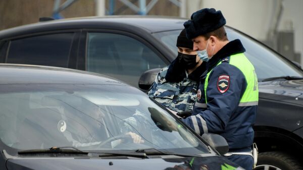 Сотрудники дорожно-патрульной службы ГИБДД проверяют документы у водителя на блокпосту при въезде в Москву на пересечении с МКАД
