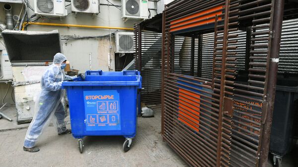 Сотрудник компании Эколайн устанавливает на место мусорный контейнер после выгрузки его содержимого в мусоровоз в одном из дворов Москвы