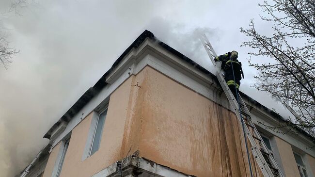 Сотрудник МЧС во время ликвидации пожара на кровле в 2-х этажного здания в Москве