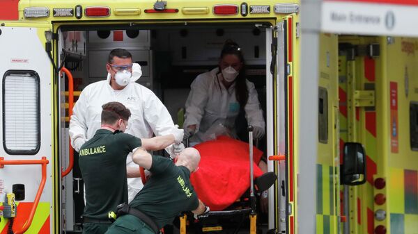 Медицинские сотрудники в защитных костюмах, доставляют пациента в больницу Святого Томаса в Лондоне, Британия
