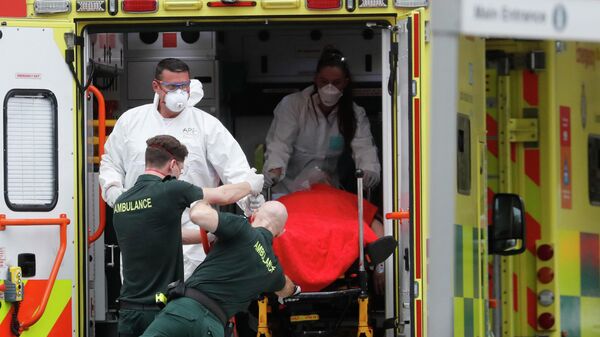 Медицинские сотрудники в защитных костюмах доставляют пациента в больницу в Британии