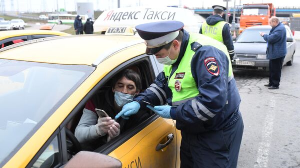 Сотрудник ДПС ГИБДД проверяет электронный пропуск у водителя такси при въезде в Москву
