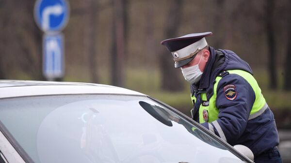 Сотрудник ДПС ГИБДД проверяет электронный пропуск у водителя при въезде в Москву