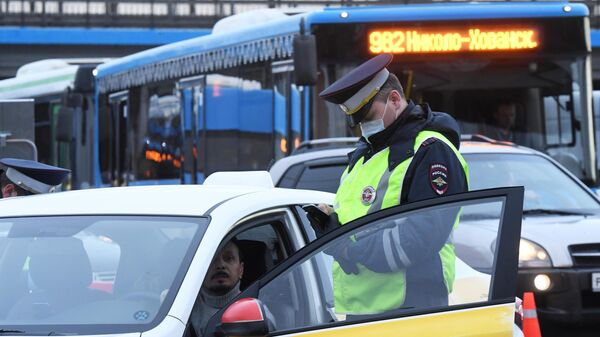 Сотрудник ГИБДД во время проверки электронного пропуска у водителя такси на блокпосту при въезде в Москву