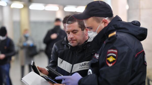 Пассажир метро показывает код своего электронного пропуска на экране смартфона сотруднику полиции на станции метро Сокольники в Москве