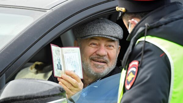 Водитель показывает документы сотруднику ГИБДД на блокпосту при въезде в Москву