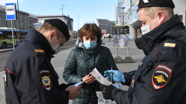 Сотрудники полиции проверяют цифровой пропуск у женщины в Москве
