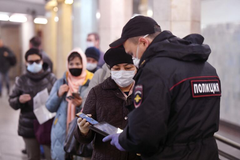 Пассажирка метро показывает код своего электронного пропуска на экране смартфона сотруднику полиции на станции метро Сокольники в Москве