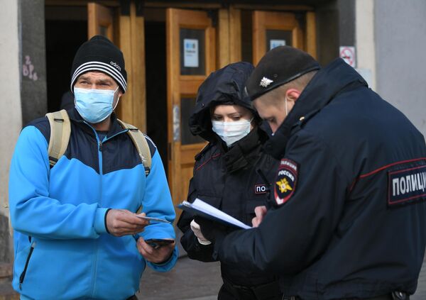 Сотрудники полиции проверяют цифровой пропуск у мужчины в Москве