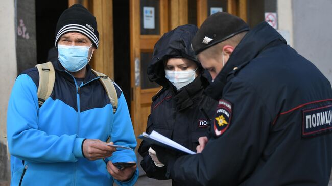 Сотрудники полиции проверяют цифровой пропуск у мужчины в Москве