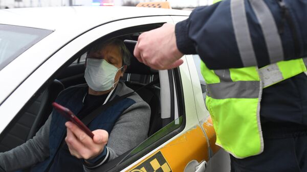 Сотрудник дорожно-патрульной службы ГИБДД во время проверки электронного пропуска у водителя такси на блокпосту при въезде в Москву