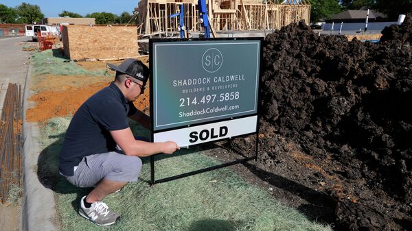 Мужчина устанавливает табличку с объявлением о продаже дома в штате Техас