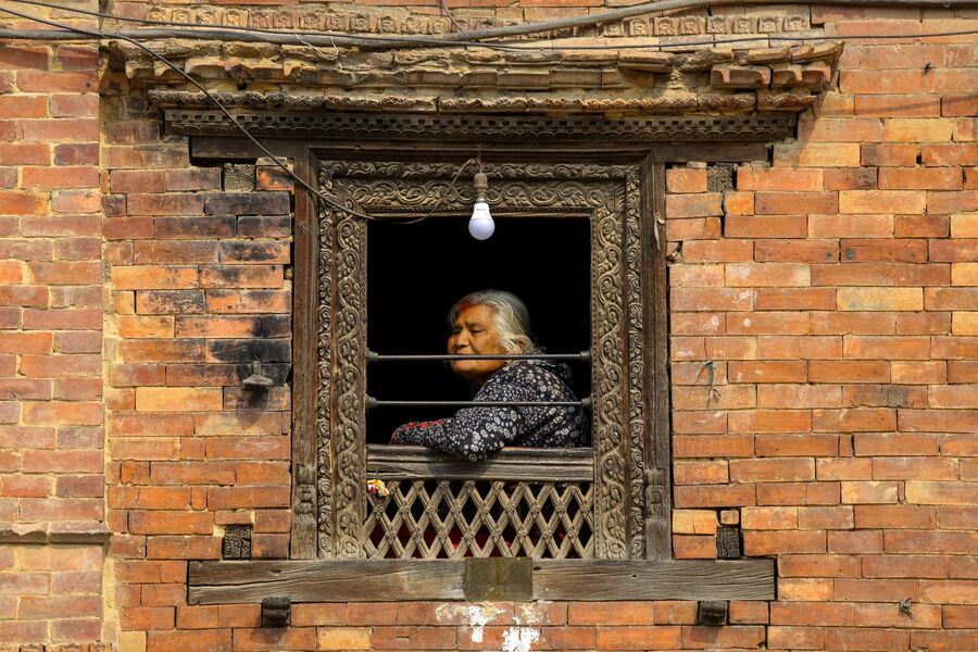 Женщина смотрит в окно в Катманду