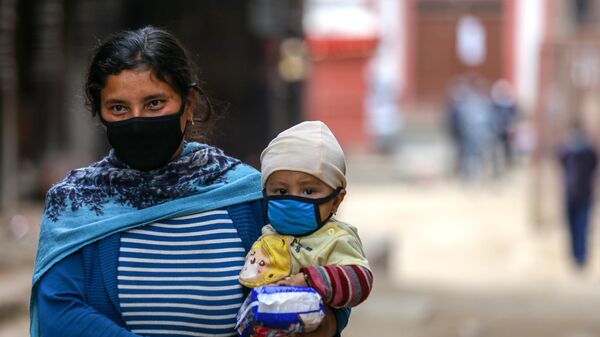 Женщина несет ребенка на руках на окраине Катманду