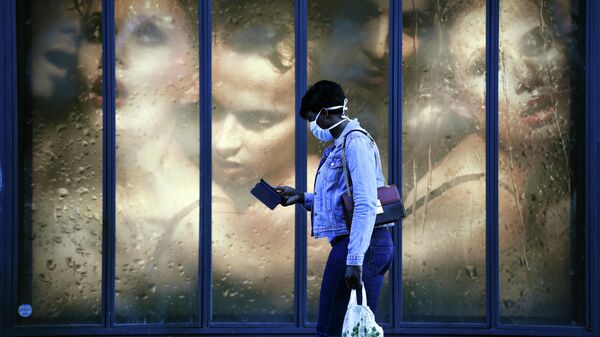 Женщина в защитной маске проходит мимо витрины магазина в Париже