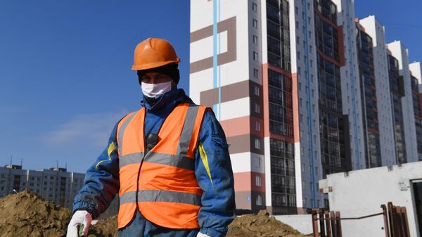 Рабочий в медицинской маске на строительстве жилого комплекса