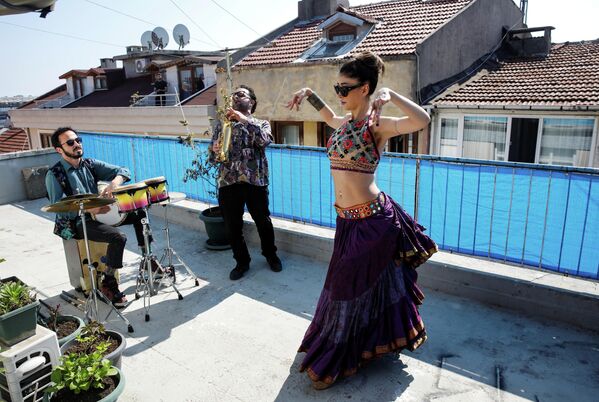 Танцовщица выступает на террасе дома в сопровождении музыкантов в Стамбуле, Турция