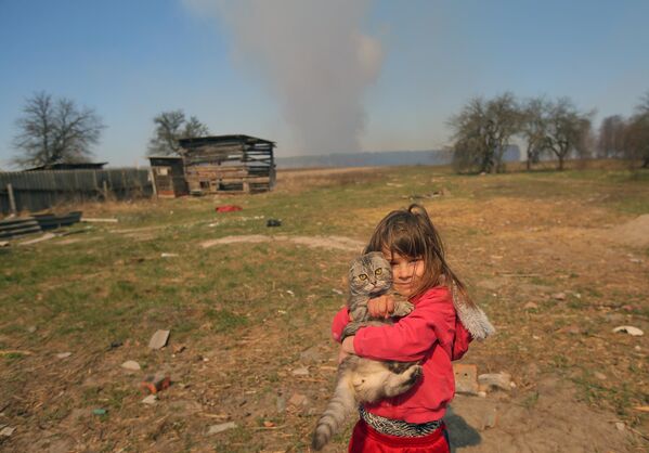 Девочка с котом во дворе частного дома в селе Раговка. Лесной пожар, возникший в районе села Полесское на территории зоны отчуждения Чернобыльской АЭС на Украине