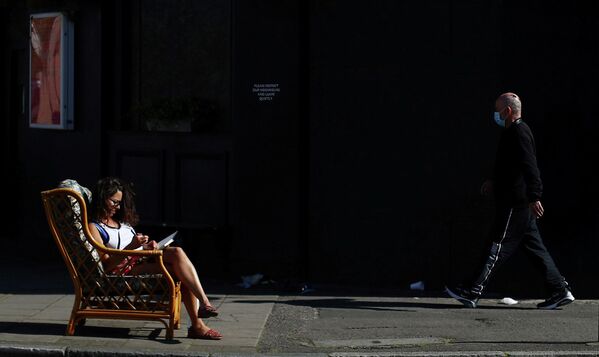 Женщина сидит на улице в Далстоне, Лондон, Великобритания