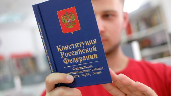 Молодой человек держит Конституцию Российской Федерации
