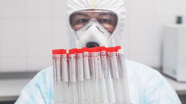 Лаборант Инвитро держит в руках пробирки с биоматериалом для тестирования на коронавирусную инфекцию