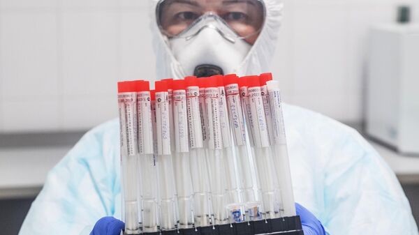 Лаборант держит в руках пробирки с биоматериалом для тестирования на коронавирусную инфекцию
