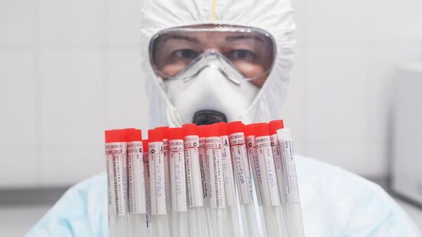 Лаборант держит в руках пробирки с биоматериалом для тестирования на коронавирусную инфекцию