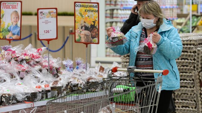 Женщина выбирает пасхальные куличи в суперрмаркете