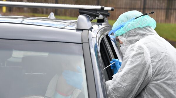 Сотрудник клиники Чайка проводит забор биоматериала для анализа на коронавирус у жителя Москвы в его машине