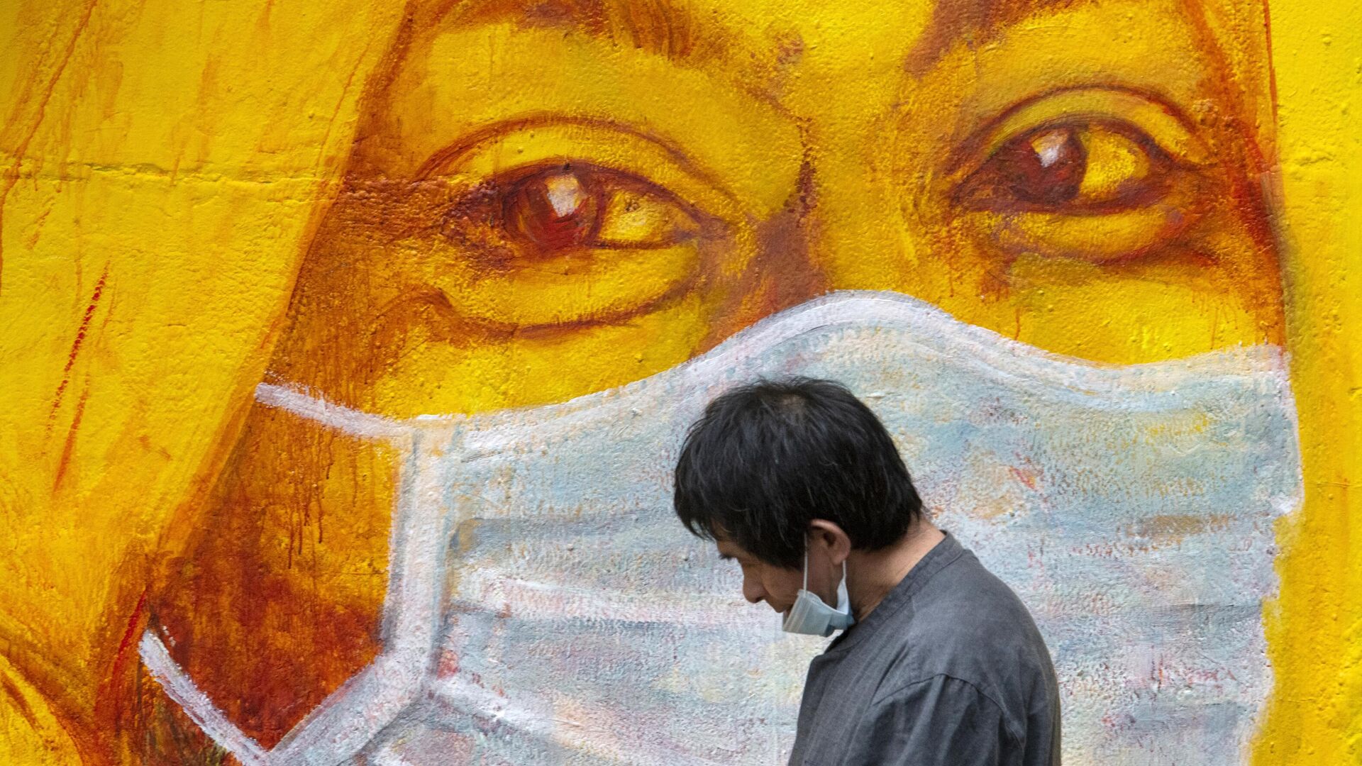 Прохожий около стены с изображением человека в маске в Гонконге - РИА Новости, 1920, 10.10.2020