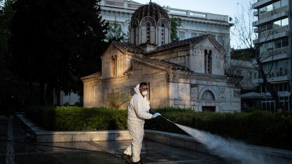 Муниципальный работник  дезинфицирует площадь вокруг собора в Афинах