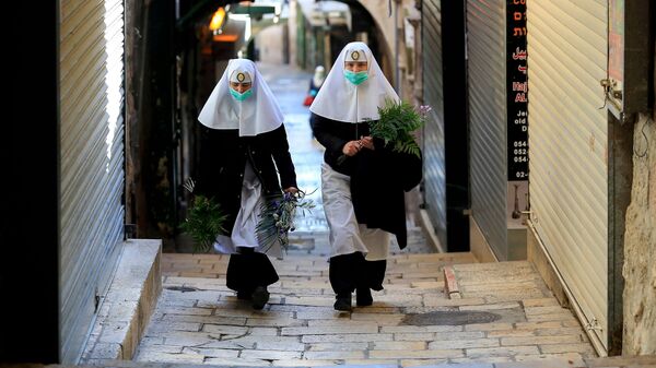 Монахини в медицинских масках идут по Виа Долороз в Вербное воскресенье в Старом городе Иерусалима