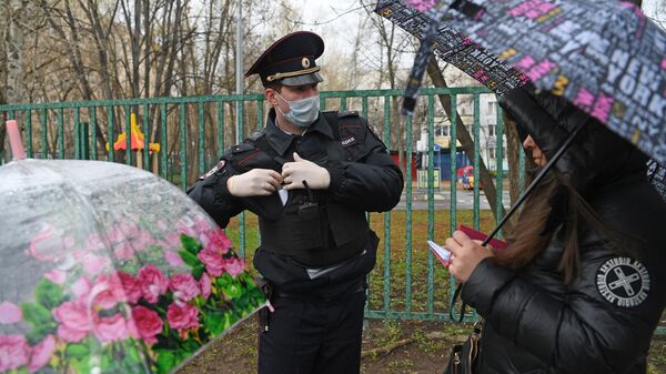 Сотрудник полиции проверяет цифровой пропуск у прохожих в Москве