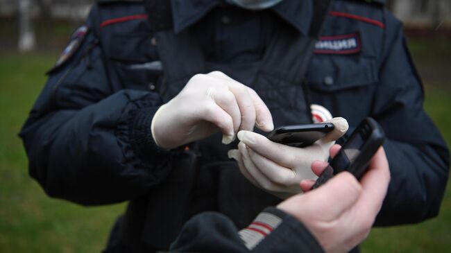 Сотрудник полиции проверяет цифровой пропуск у прохожего в Москве