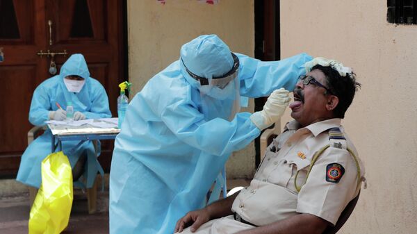 Врач берет мазок на коронавирус в бесплатном медицинском центре в трущобах Дхарави в Мумбаи, Индия