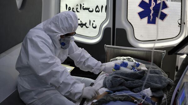 Сотрудник скорой медицинской помощи перевозит пациента с коронавирусом в больницу в Тегеране, Иран