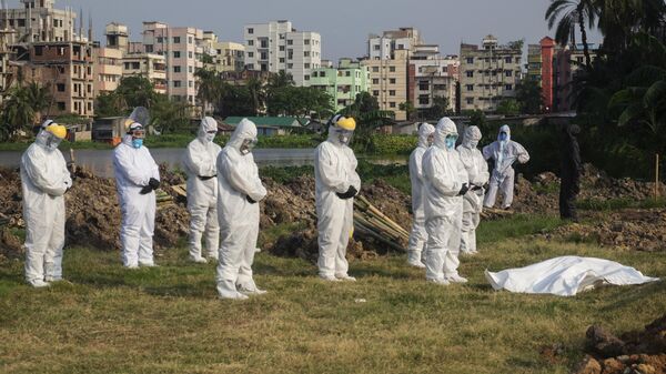 Добровольцы и медики в защитных костюмах во время похорон человека, умершего от коронавируса, на кладбище в Бангладеш