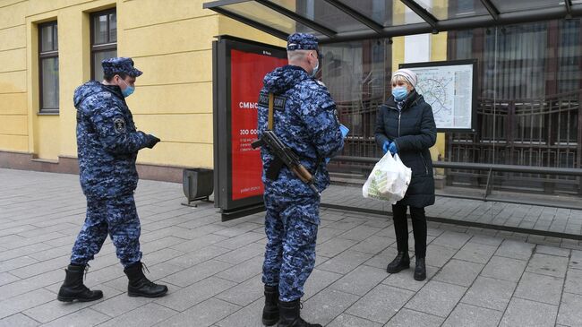 Сотрудники Росгвардии проверяют цифровой пропуск у женщины в Москве