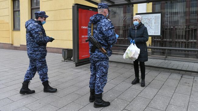 Сотрудники Росгвардии проверяют цифровой пропуск у женщины в Москве