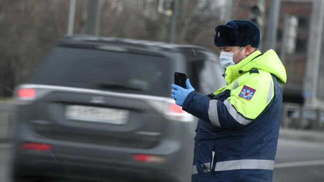 Инспектор дорожно-патрульной службы проверяет у водителя цифровой пропуск на передвижение по Москве