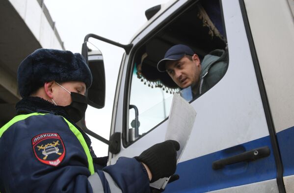 Инспектор дорожно-патрульной службы проверяет у водителя цифровой пропуск на передвижение по Москве