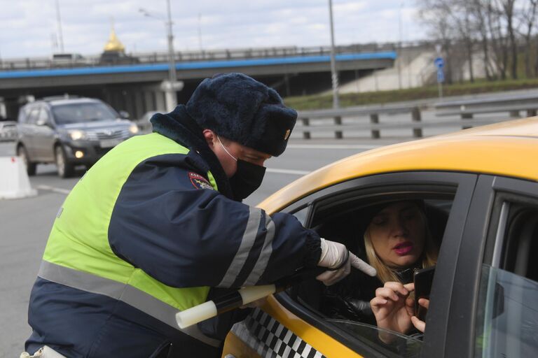 Инспектор дорожно-патрульной службы проверяет у пассажира такси цифровой пропуск на передвижение по Москве