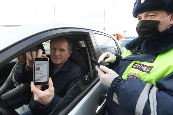 Инспектор дорожно-патрульной службы проверяет у водителя цифровой пропуск на передвижение по Москве
