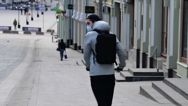 Молодой человек в защитной маске на самокате на улице Кузнецкий мост в Москве 