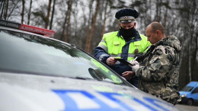 Инспектор дорожно-патрульной службы проверяет у водителя цифровой пропуск на передвижение по Москве