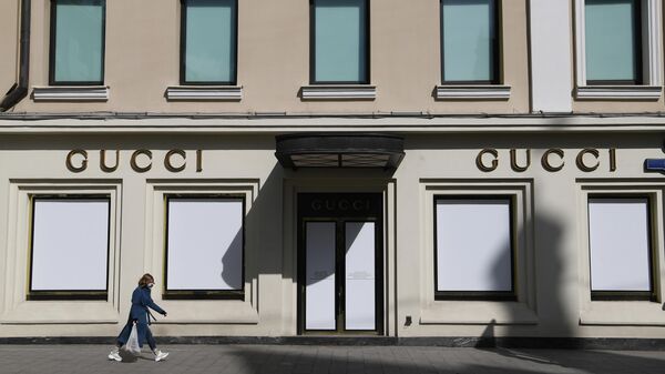 Девушка в защитной маске проходит мимо витрин закрытого магазина Gucci на улице Петровка в Москве